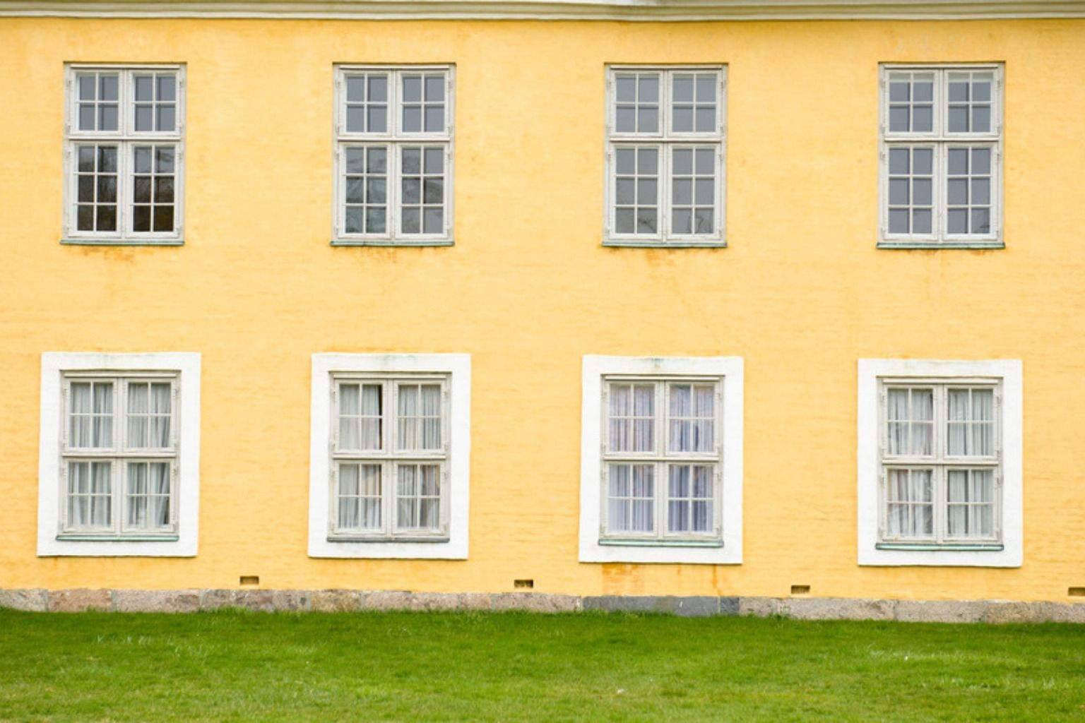 Gul pudset facade med to rækker hvide sprossevinduer