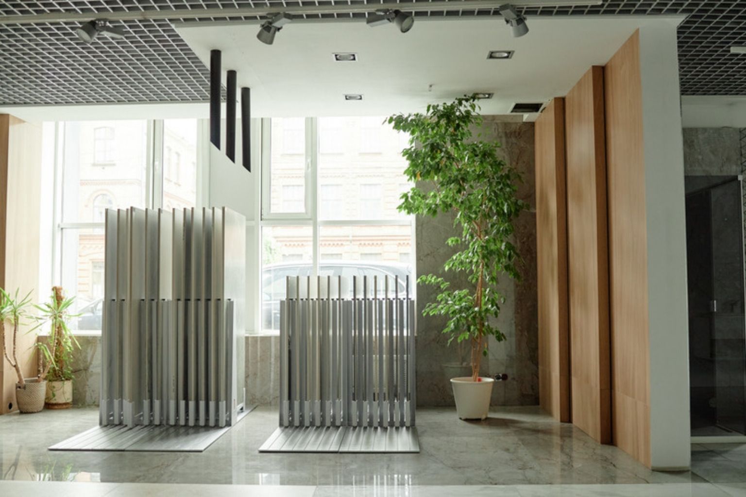 Lyst showroom med stativer af materialeprøver, træpaneler og en stor plante